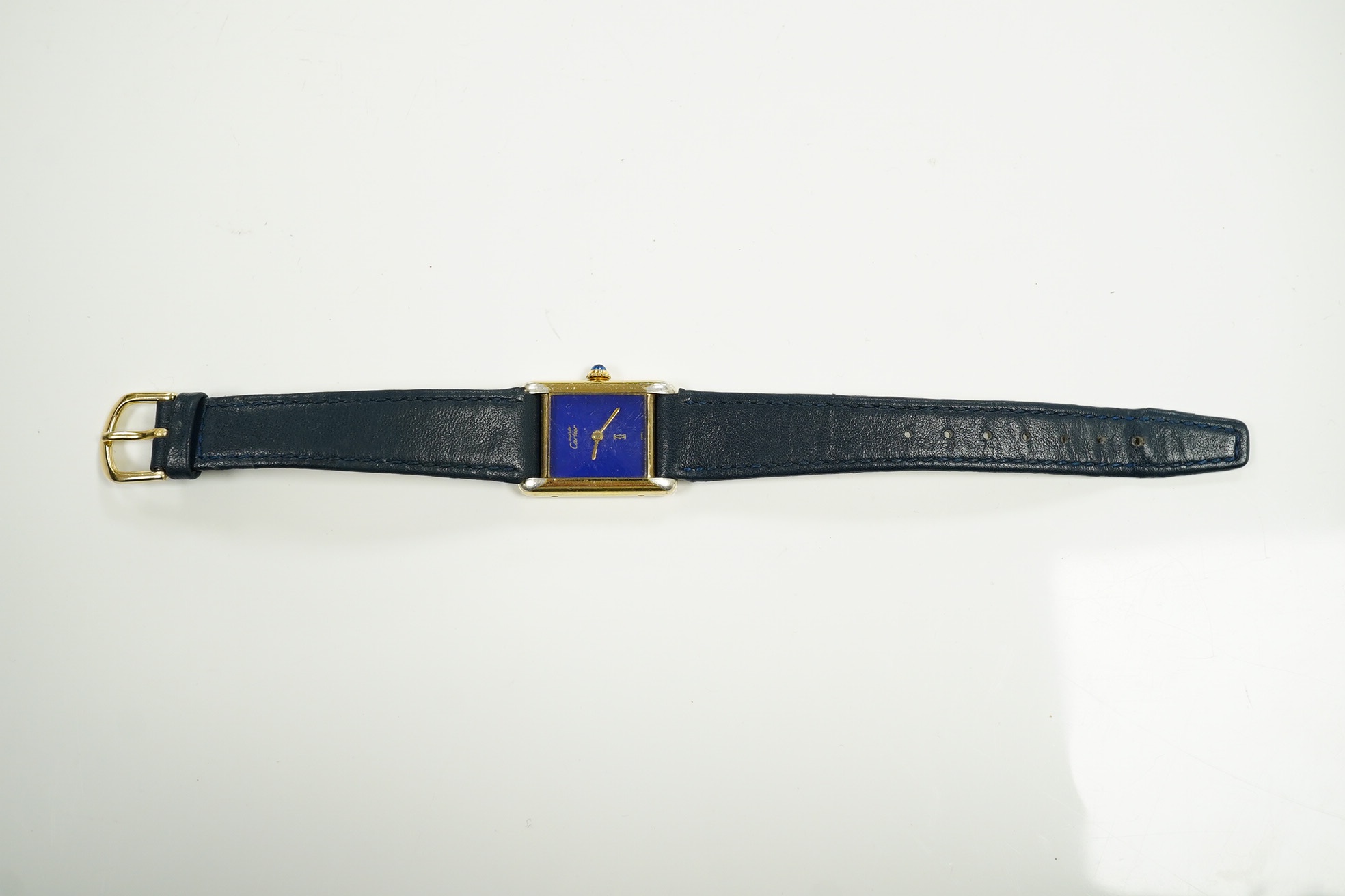 A lady's gilt 925 Must De Cartier manual wind wrist watch, with lapis lazuli rectangular dial and cabochon sapphire set winding crown, on an associated leather strap, case diameter 20mm, no box or papers. Condition - poo